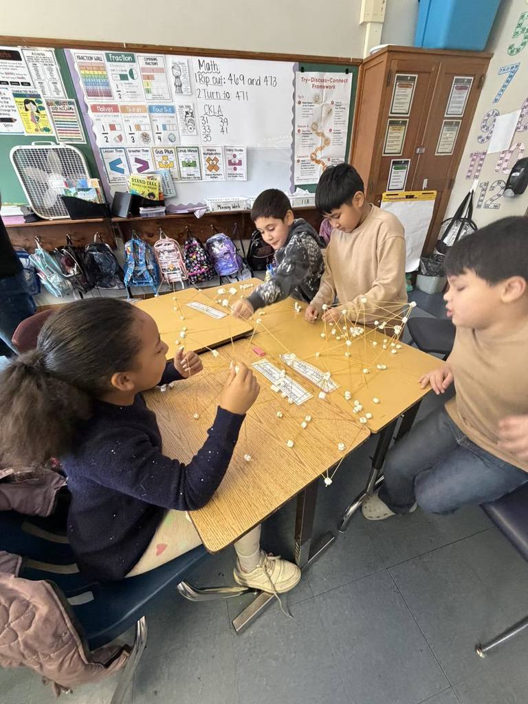 Students making something out of spaghetti and marshmallows. 