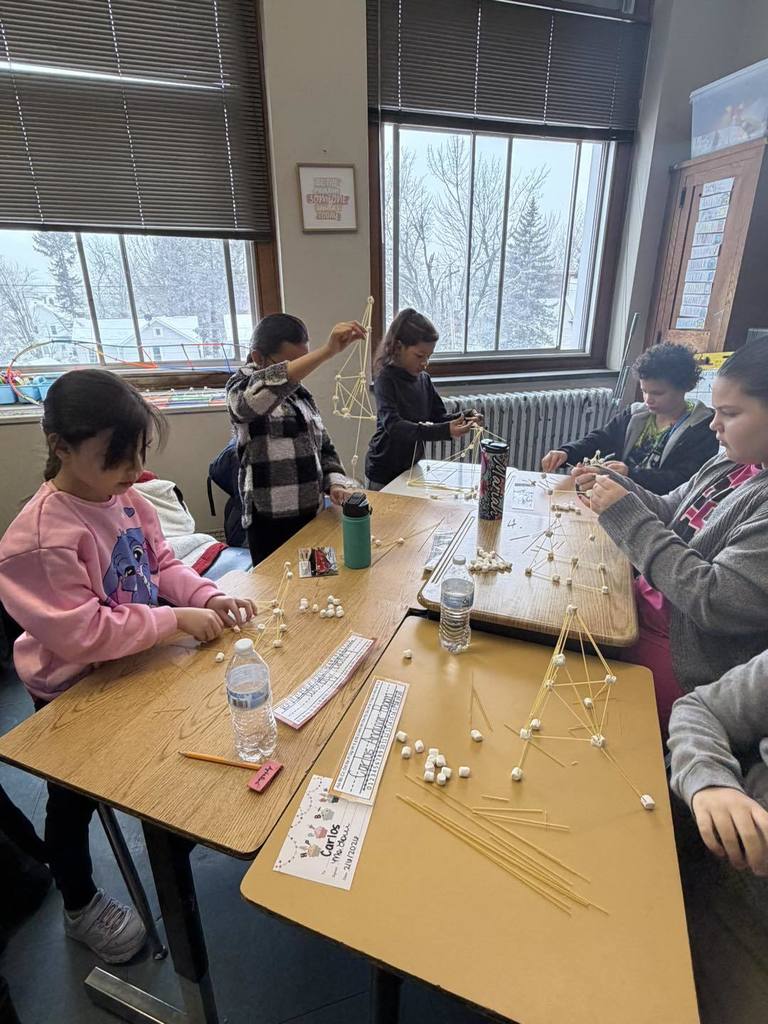 Students making something out of spaghetti and marshmallows. 
