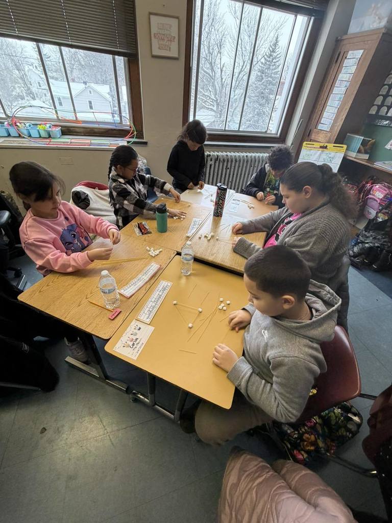 Students making something out of spaghetti and marshmallows. 