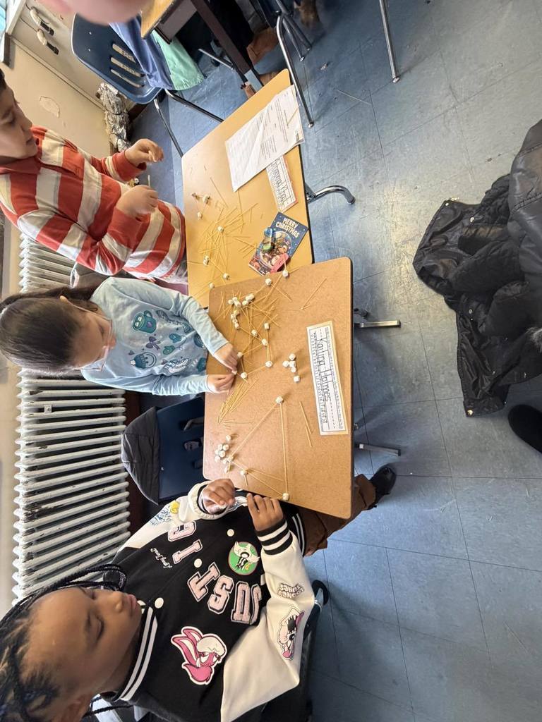 Students making something out of spaghetti and marshmallows. 