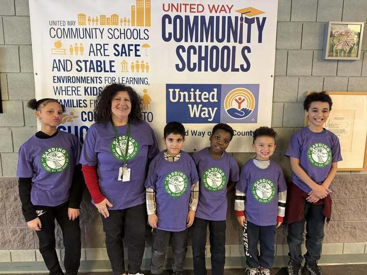 Kids and adult wearing a purple shirt that has the Harding Elementary School logo on it.