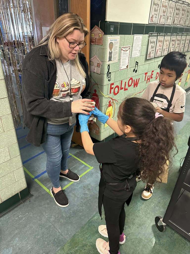A student handing an adult a cup of coffee. 