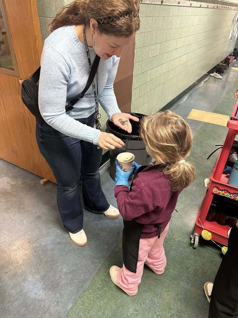 Adult putting money into a cup that a young girl is holding. 