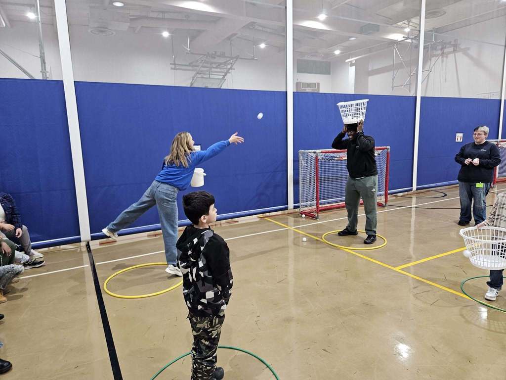 Kids and adults playing games in a gym.