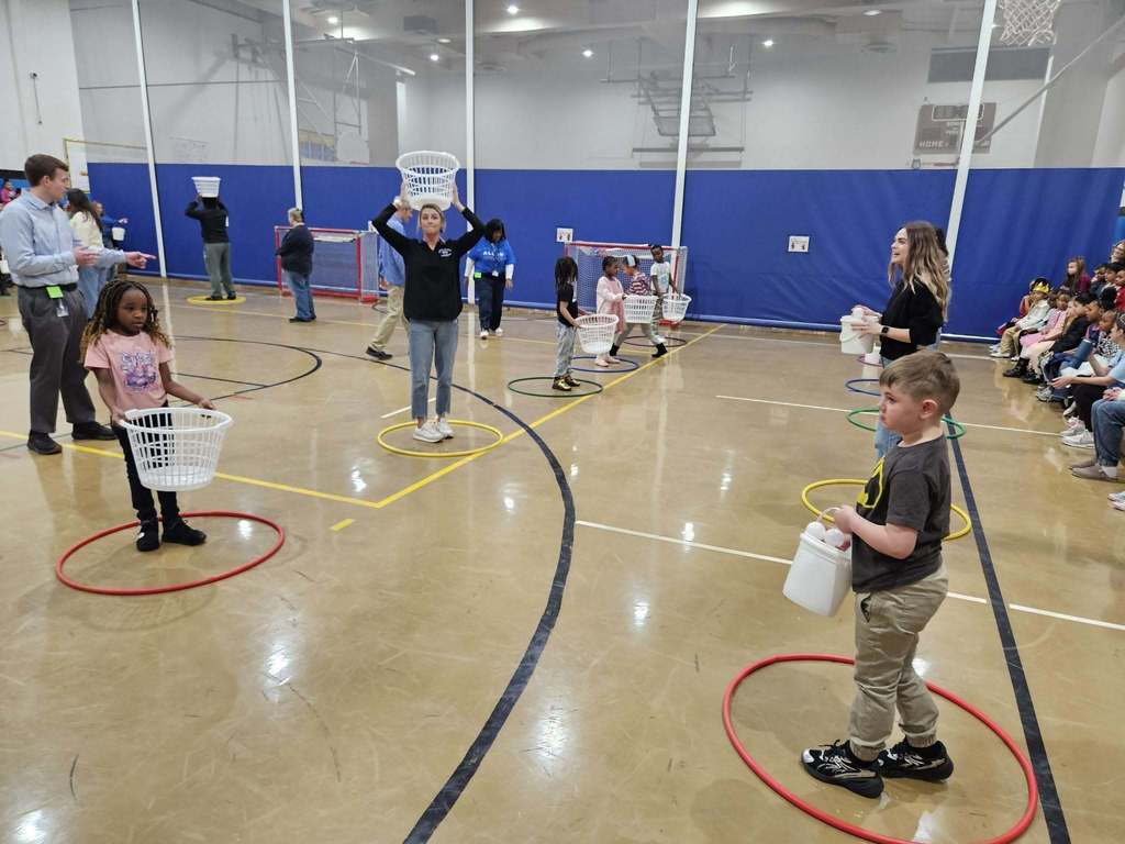 Kids and adults playing games in a gym.