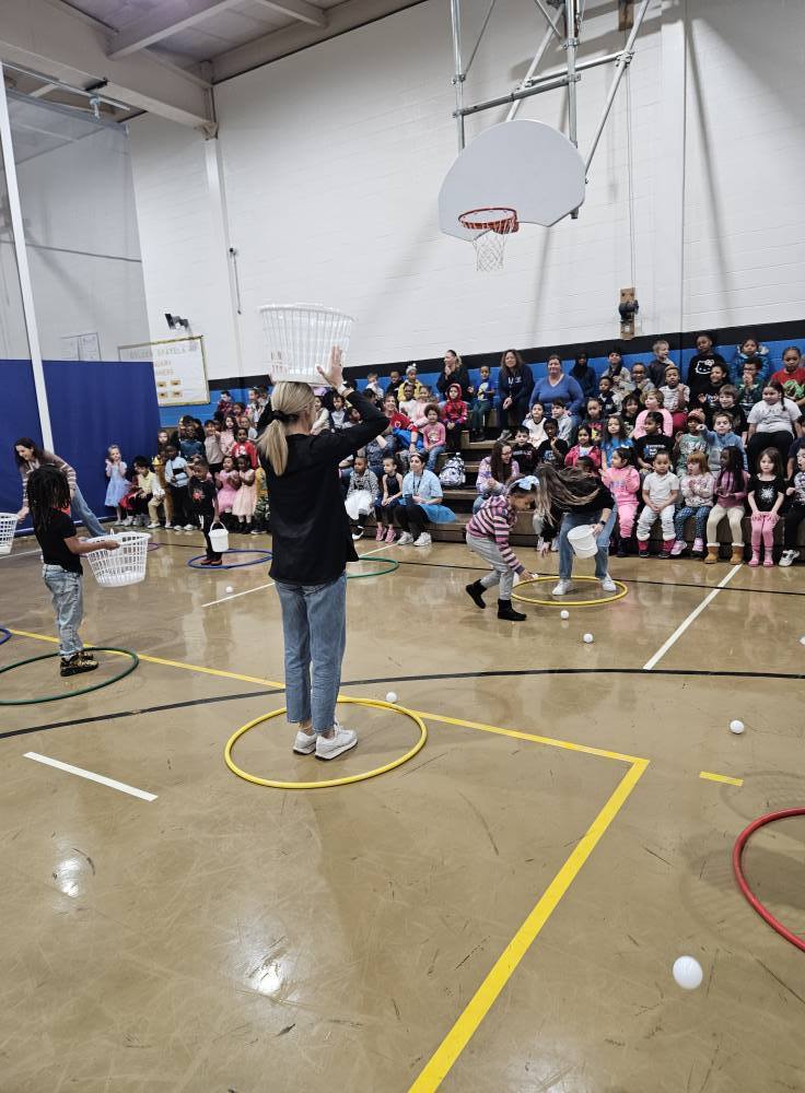 Kids and adults playing games in a gym.