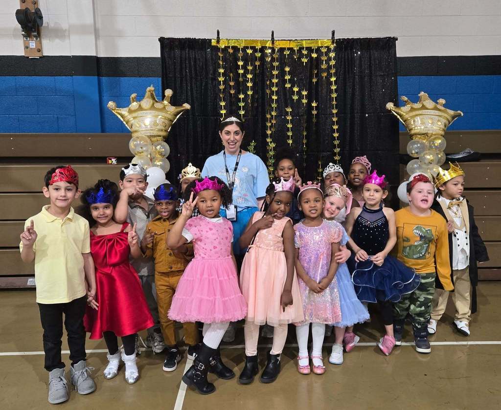 Students and teacher dressed up and they are all wearing crowns.