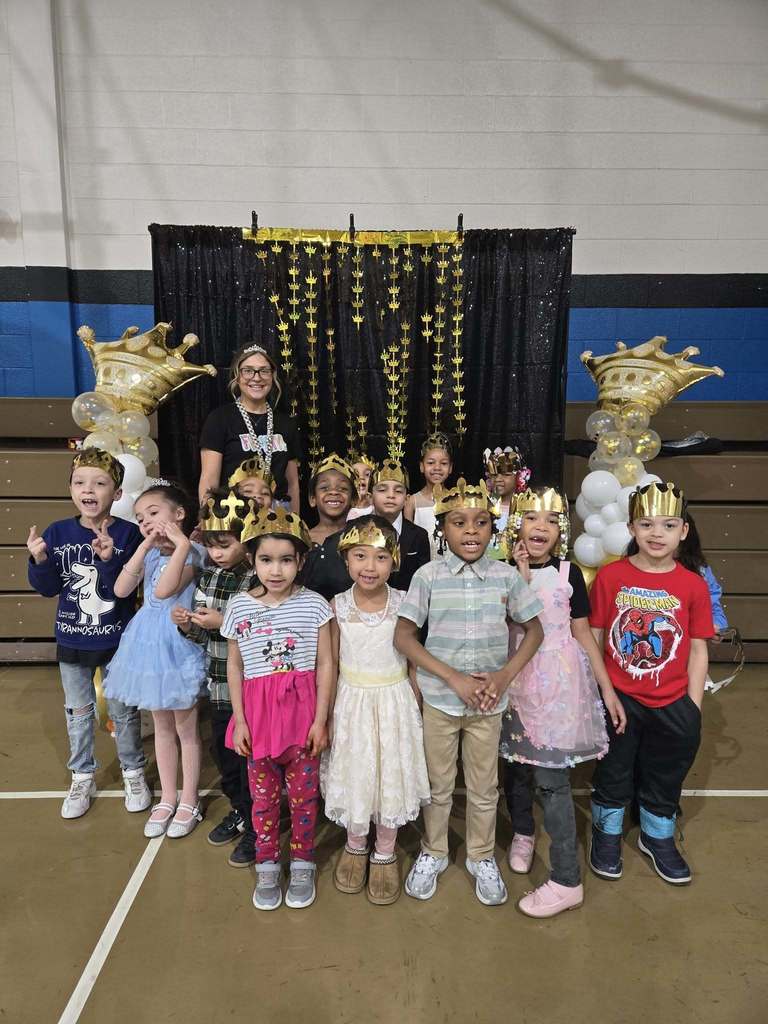 Students and teacher dressed up and they are all wearing crowns.