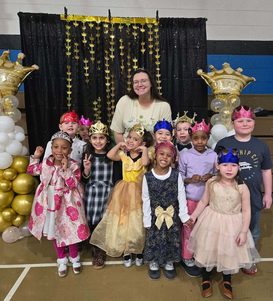 Students and teacher dressed up and they are all wearing crowns.