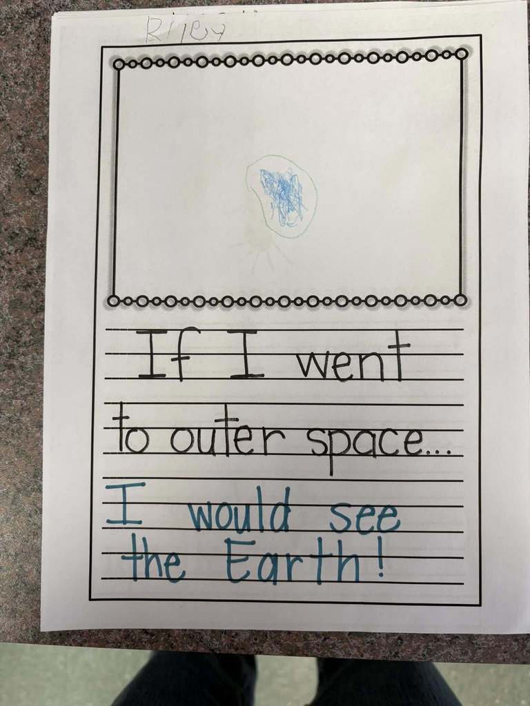 Writing on paper of what students would see if they went to outer space.