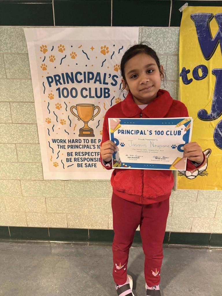 Young child dressed in all red is holding up their certificate. 