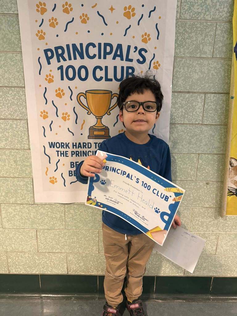 Young child dressed in a blue shirt is holding up their certificate. 