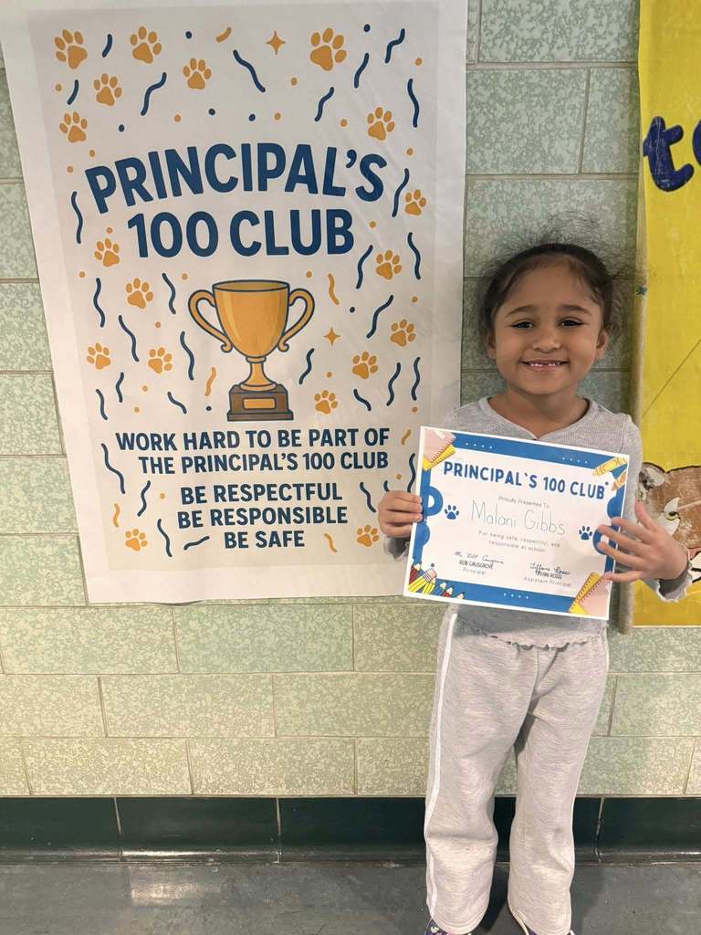 Young child dressed in a gray shirt is holding up their certificate. 