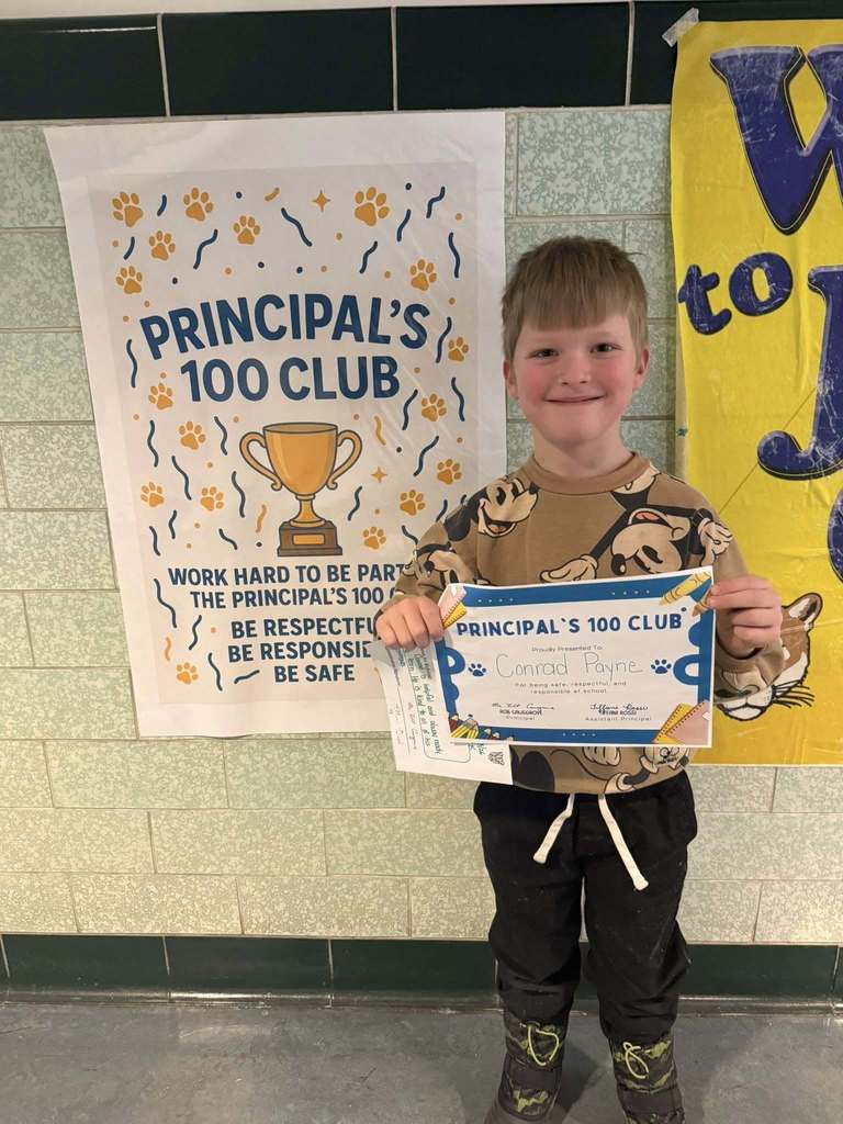 Young child dressed in a tan micky mouse shirt is holding up their certificate. 