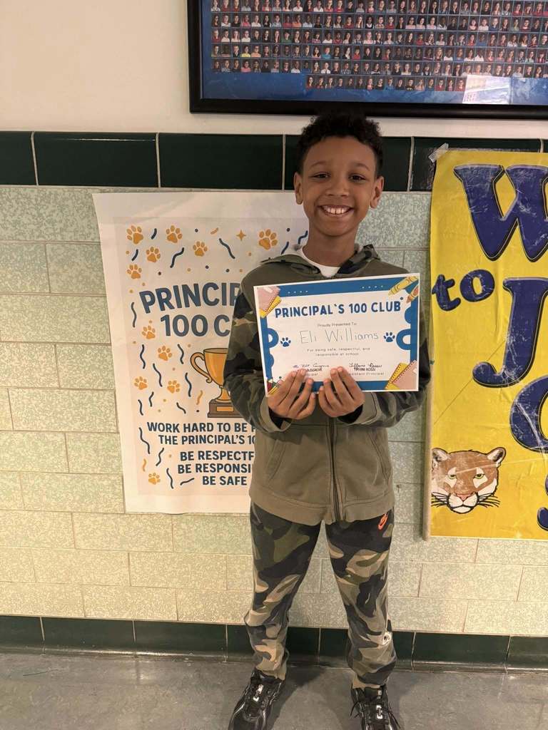 Young child dwearing camouflage pants is holding up their certificate. 