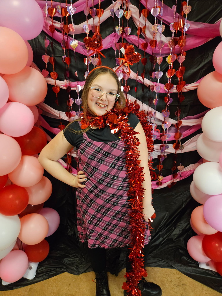 Young girl standing in front of pink, red, and white decorations. 