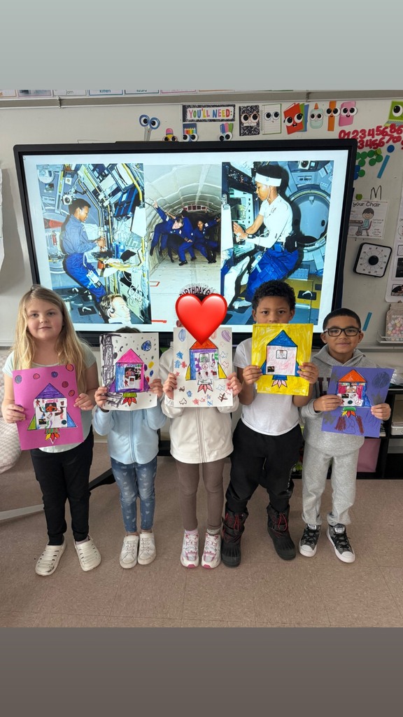 Kids showing their artwork in a classroom.