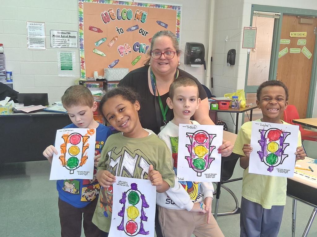 Kids showing their artwork in a classroom.