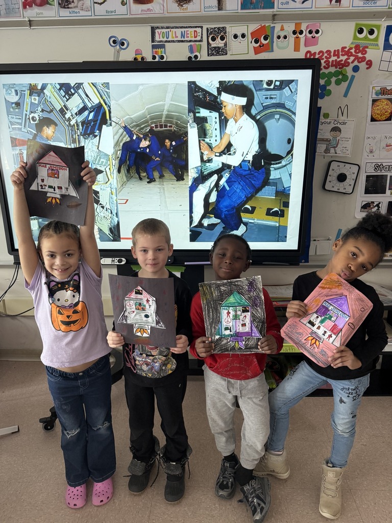 Kids showing their artwork in a classroom.