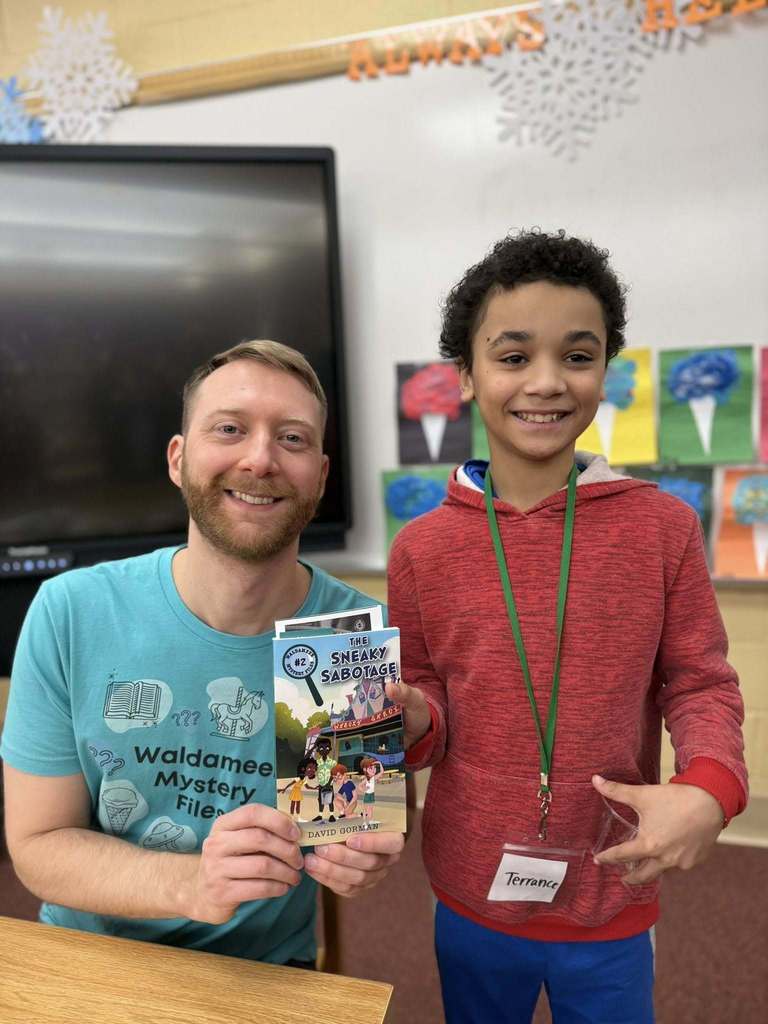 A man in a blue shirt is next to a kid that is holding a book.