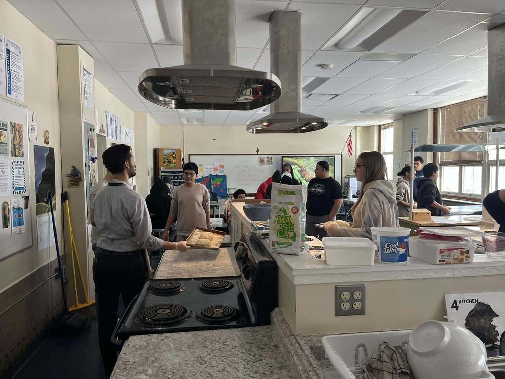 Students in a kitchen and teacher talking to them.