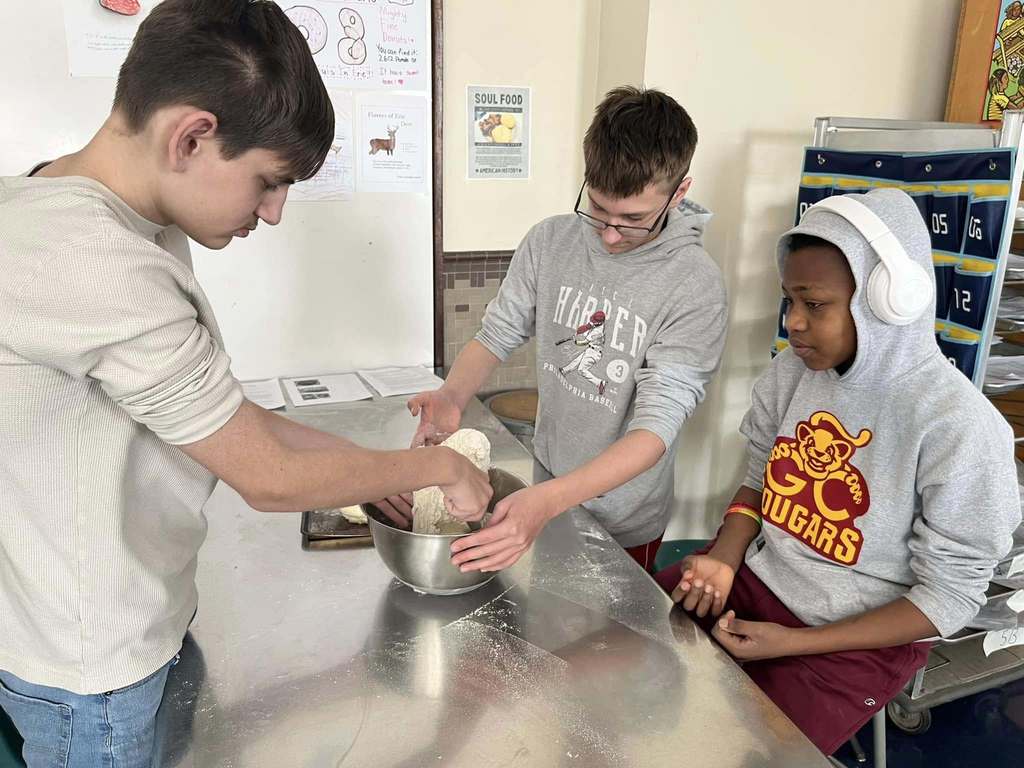 Kids making bread and mixing in a mixing bowl.