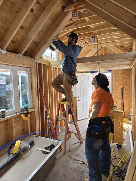 A man working inside a house that has plywood everywhere.
