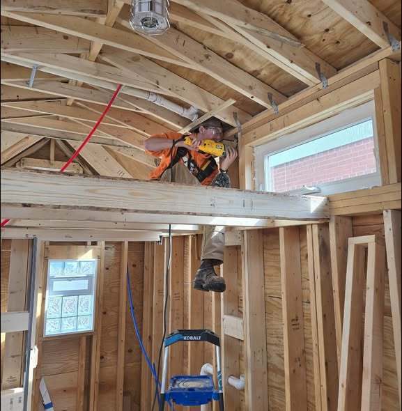 A man working inside a house that has plywood everywhere.