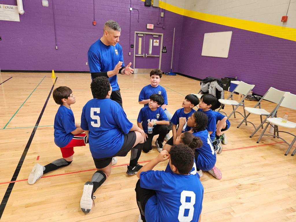 A group of kids looking up to their coach talking.