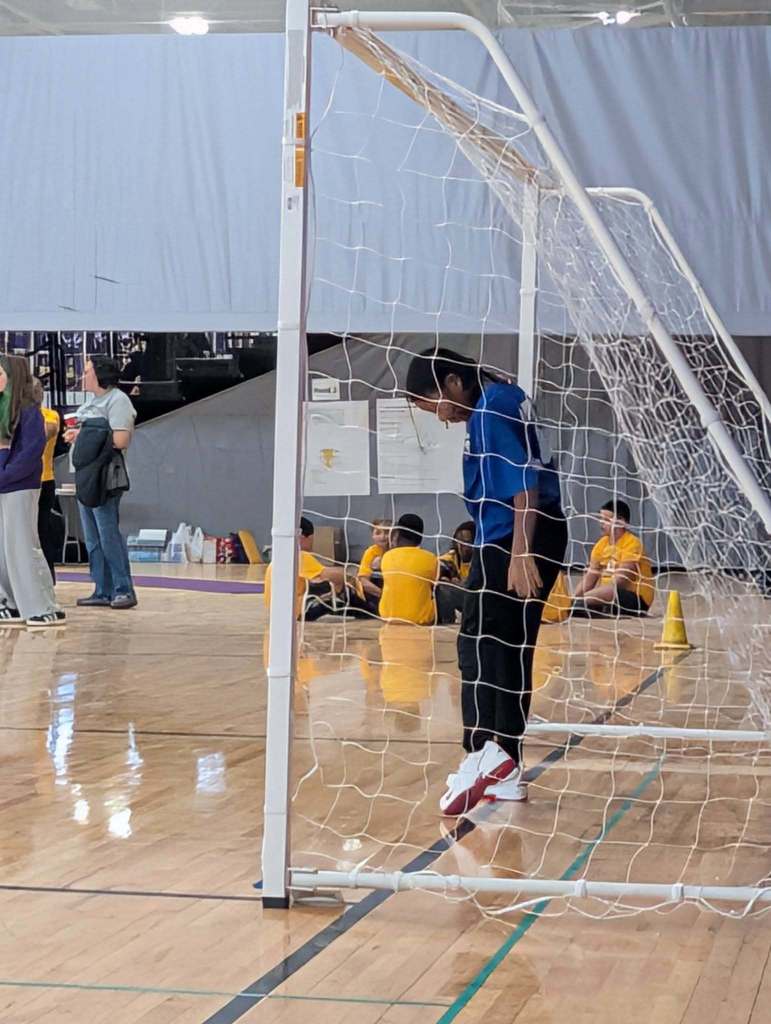 A student standing in a soccer net.