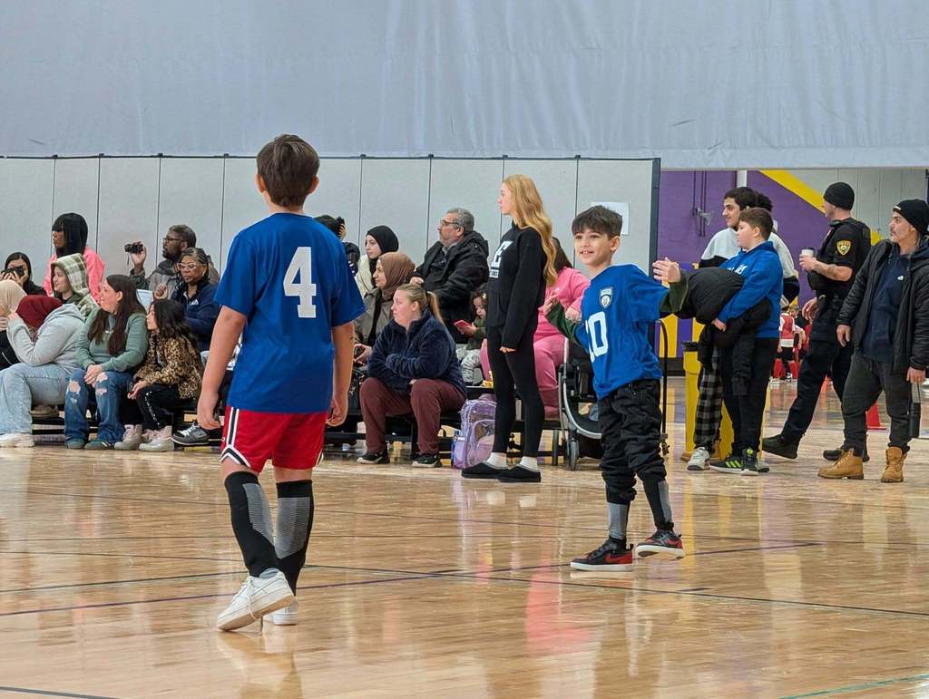 Kids playing soccer in a school gym.