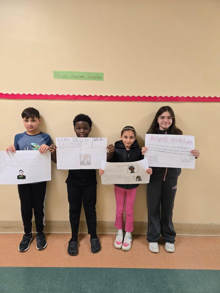 A group of students holding up white paper that has drawings and writing on it.