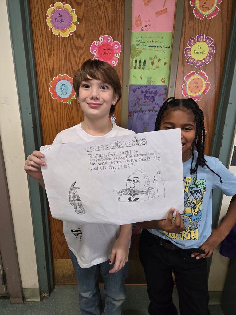 Two students showing a paper with a drawing and writing on it.
