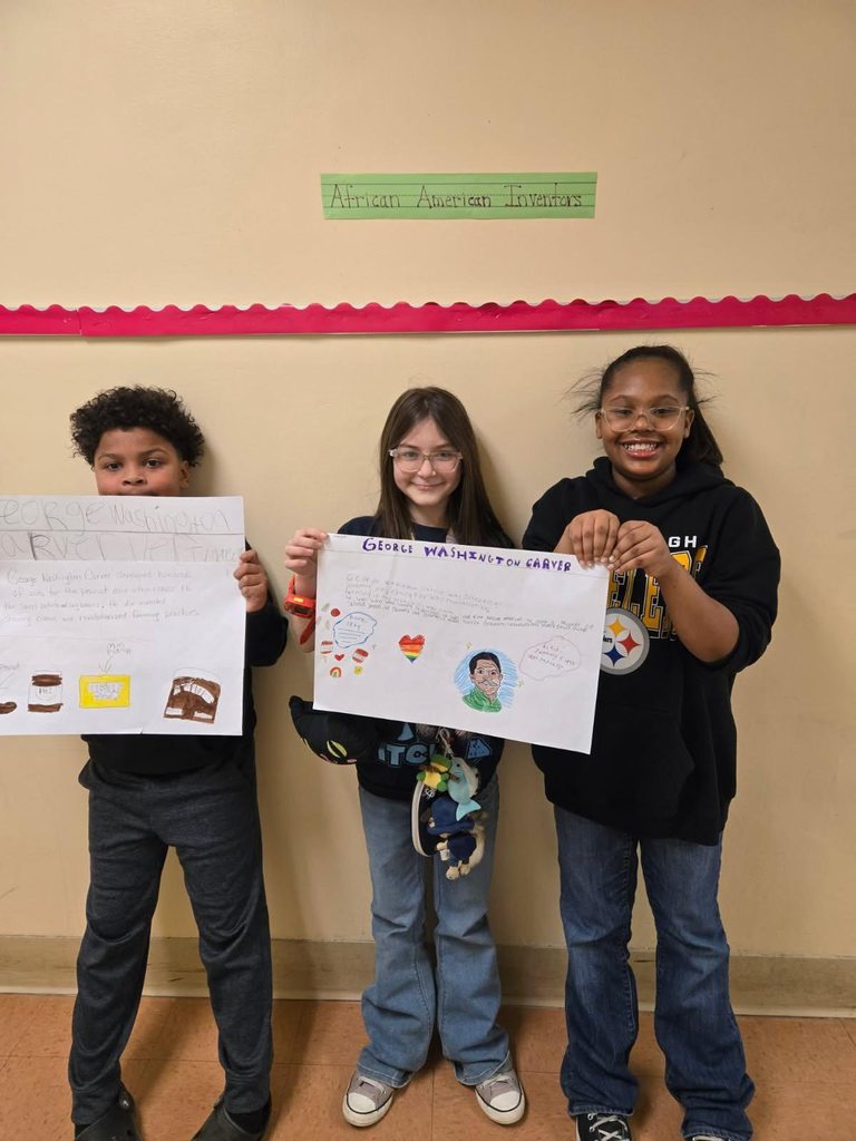 A group of students holding up white paper that has drawings and writing on it.