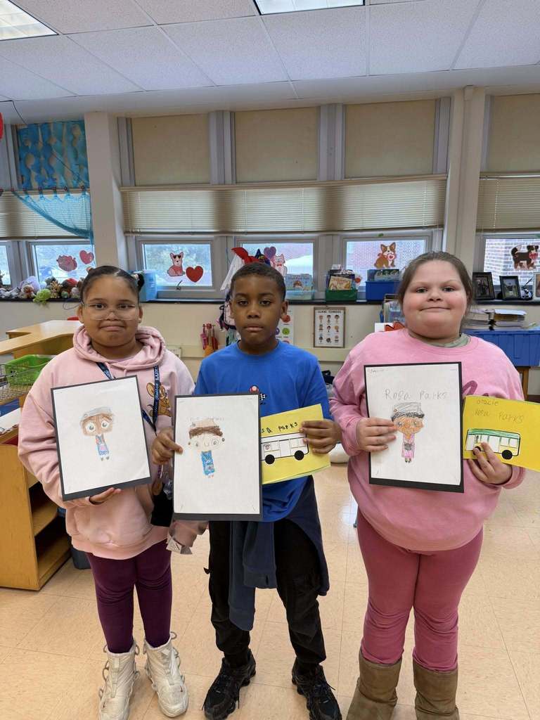 A group of students holding up white paper that has drawings and writing on it.