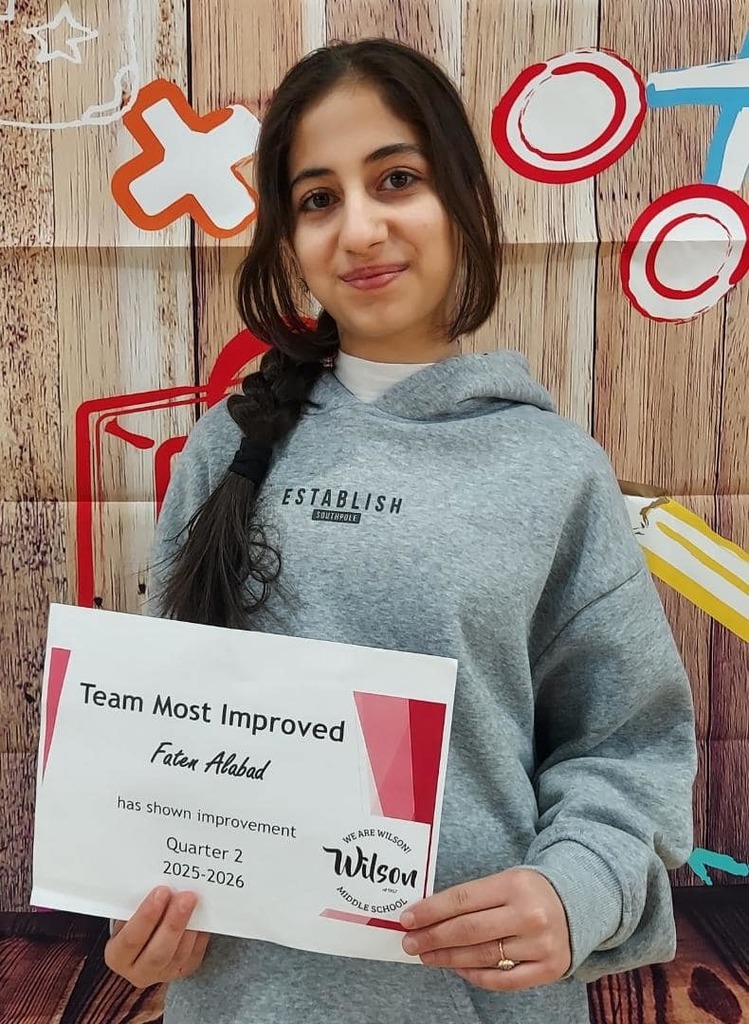 Young girl wearing a gray hoodie is holding her certificate. 