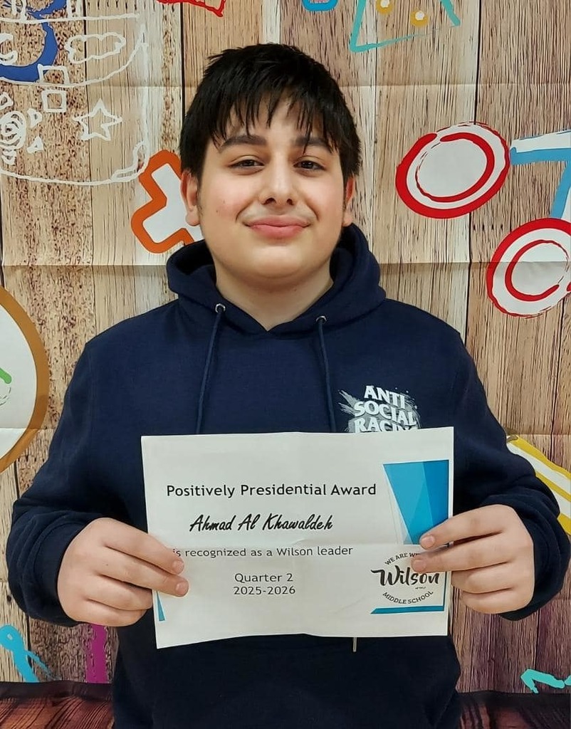 Young boy wearing a blue hoodie is holding her certificate. 