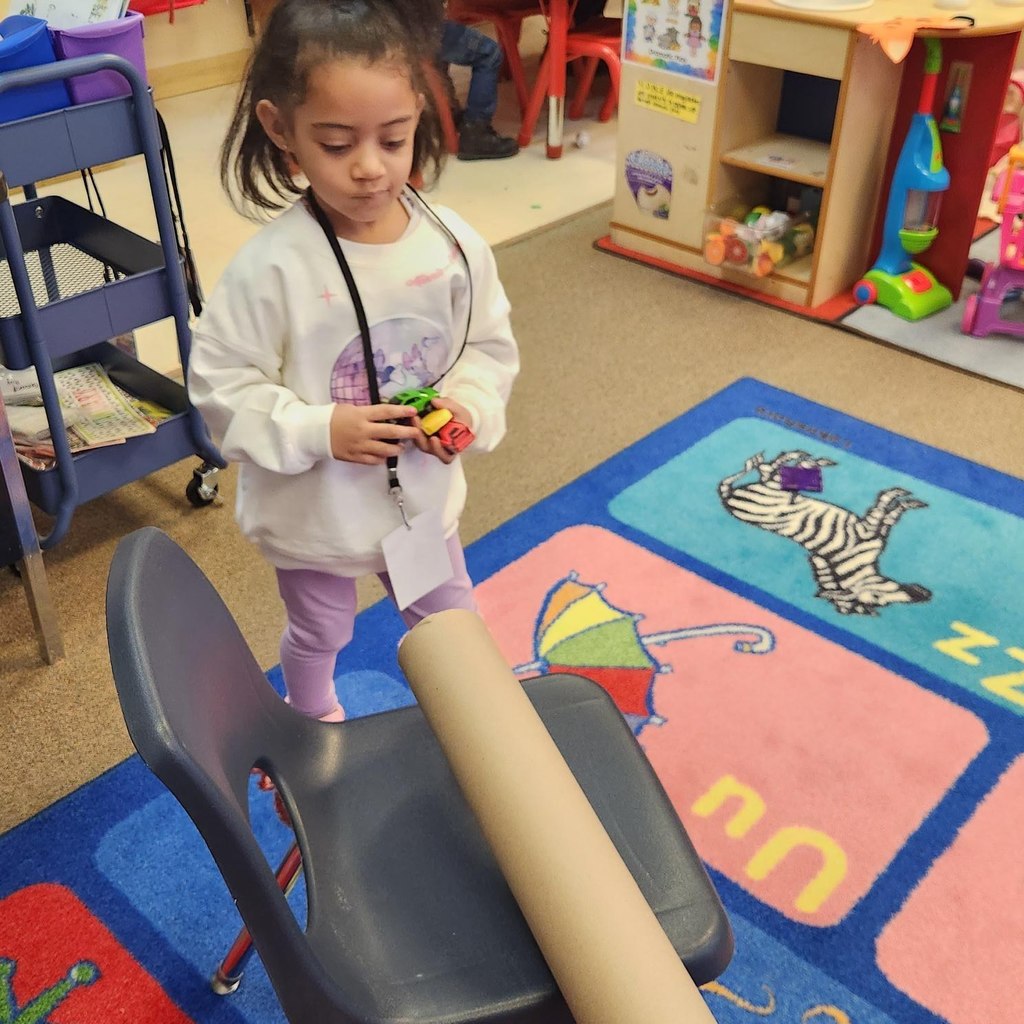 Kid playing with cars and a tube.