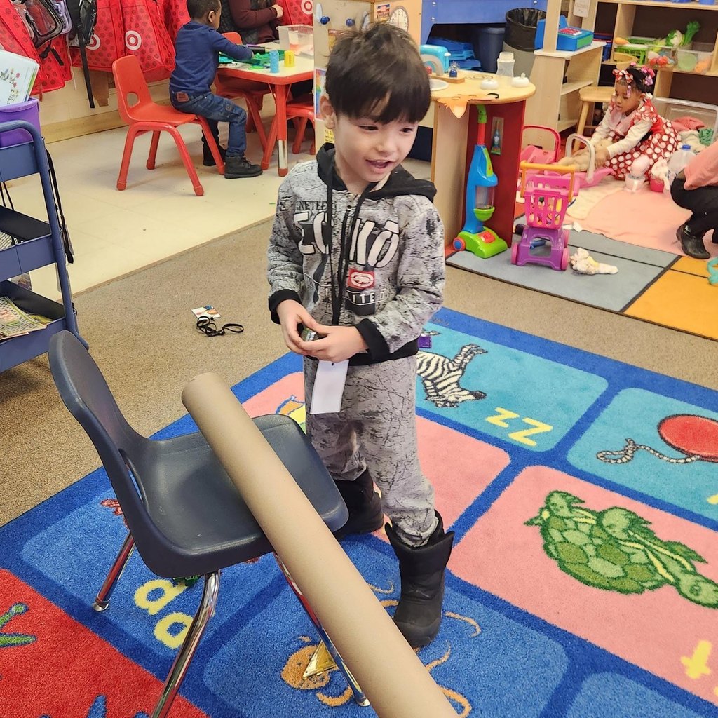 Kid playing with cars and a tube.