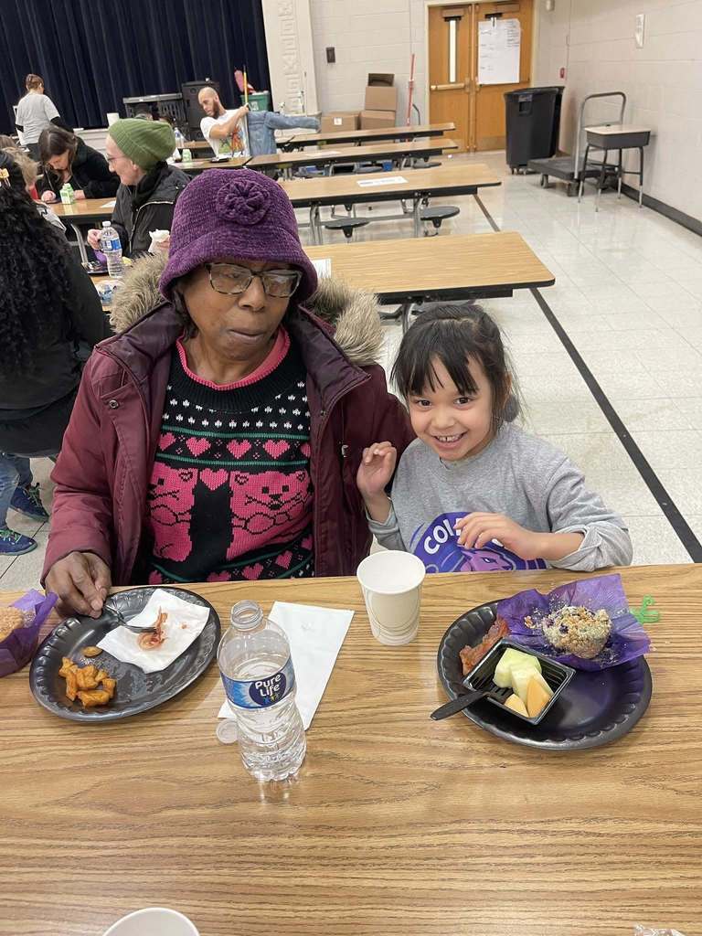 A women and young girl smiling in a school cafeteria. 