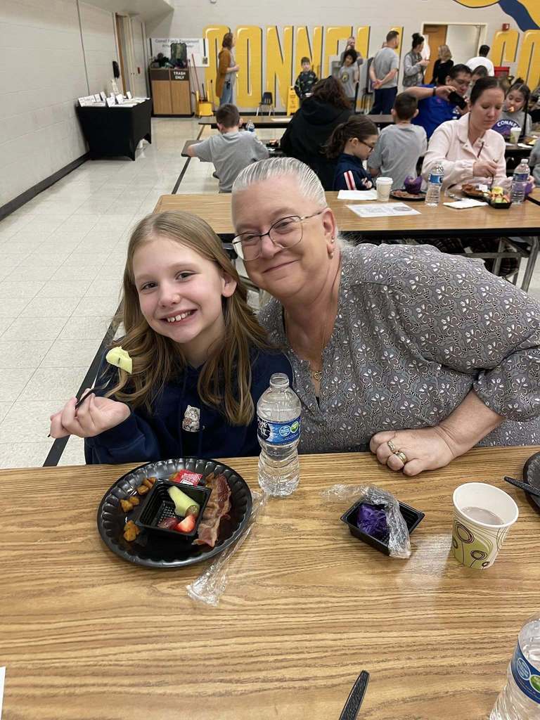 A women and young girl smiling in a school cafeteria. 
