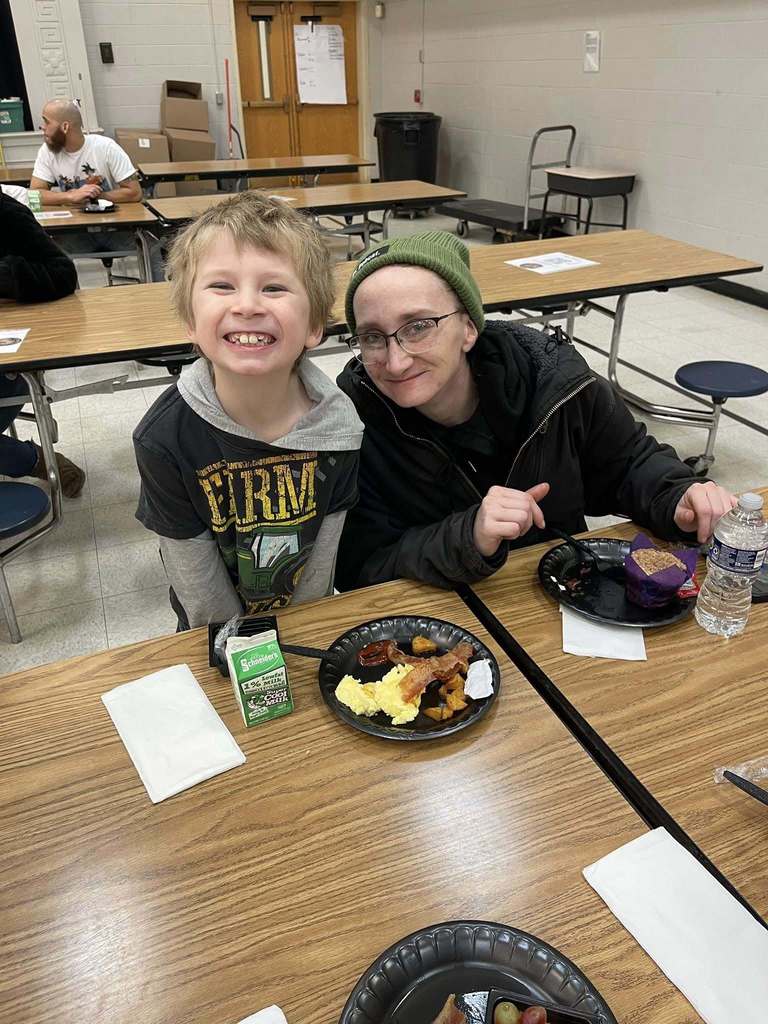 A women and young boy smiling in a school cafeteria. 