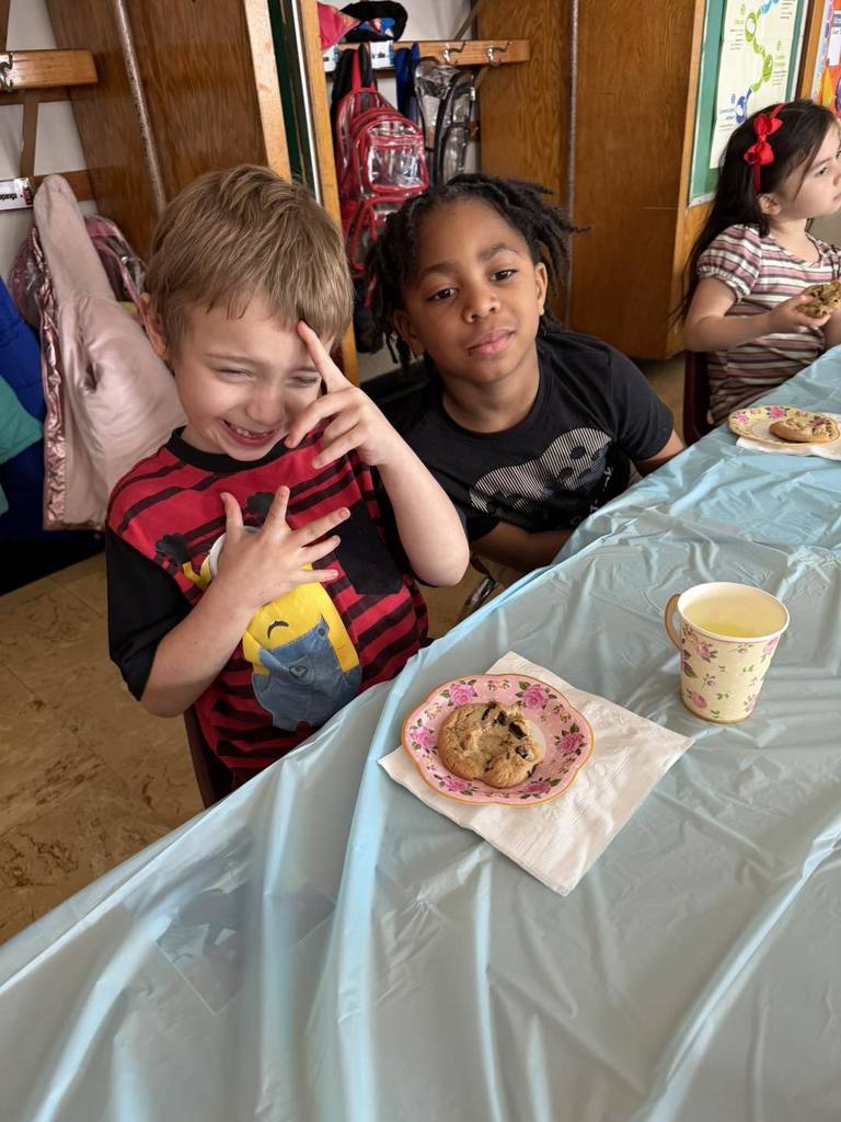 Kids smiling with cookies and juice in front of them. 