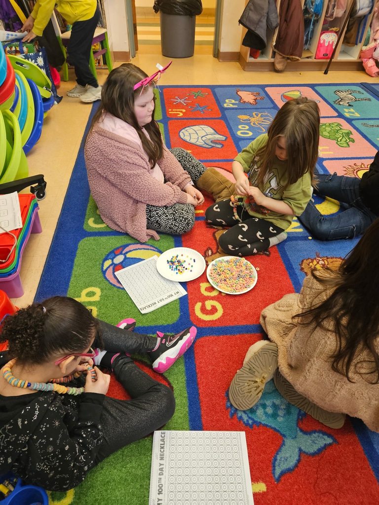 Kids sitting on a colorful rug in a classroom with snacks on a plate.