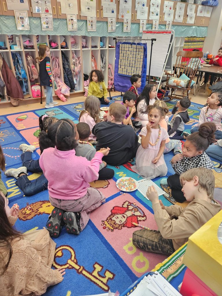 Kids sitting on a colorful rug in a classroom.