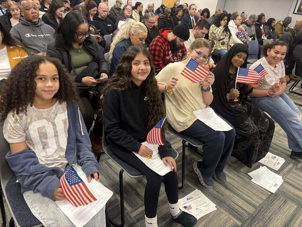 Kids sitting in chairs and holding the United States of America Flags.