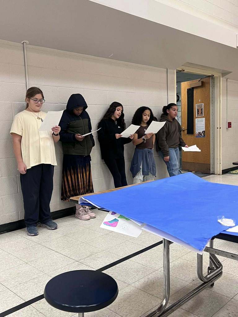 Kids reading papers while standing.