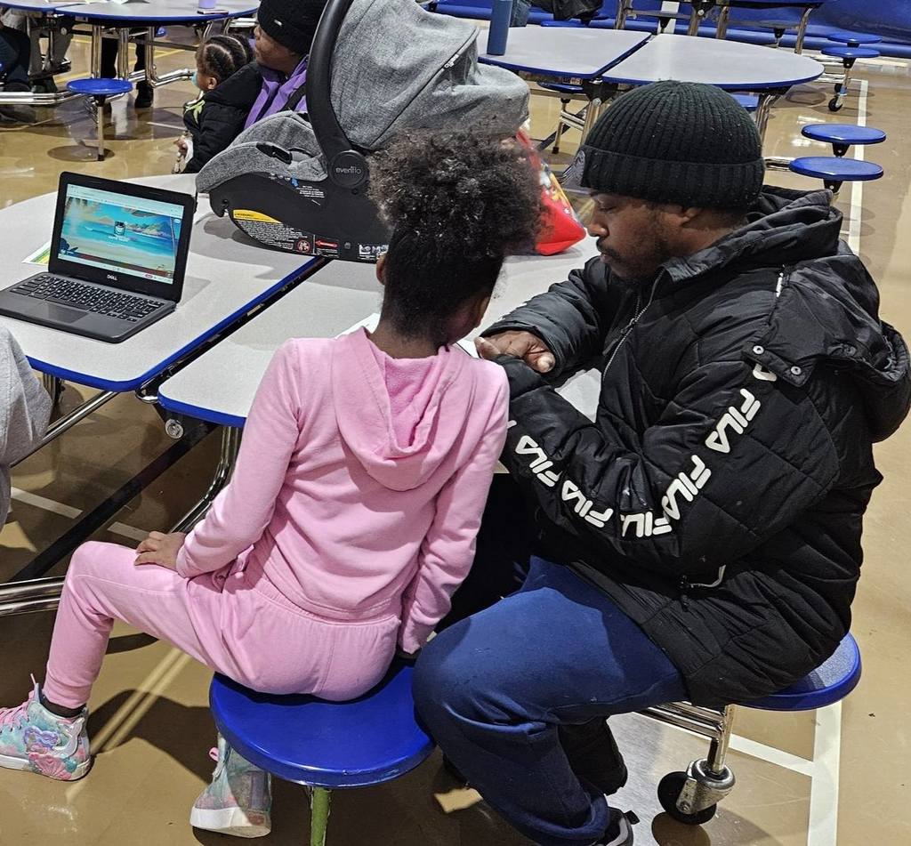 Young girl in pink sitting next to a man in a black jacket.