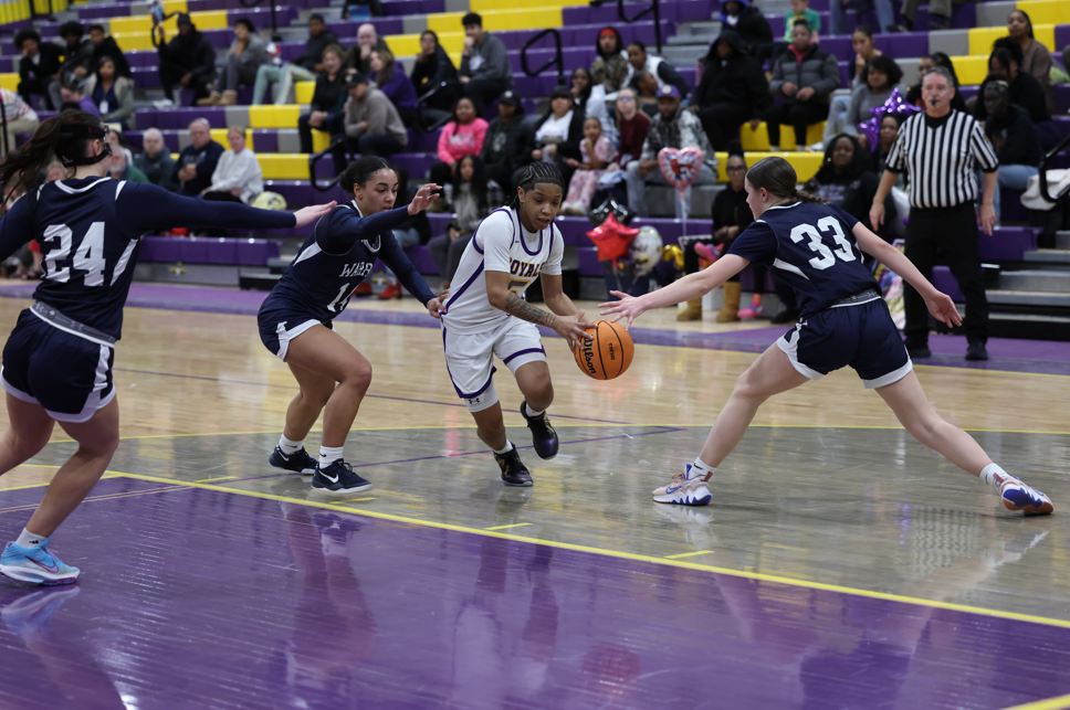 Lady's playing basketball on the court.