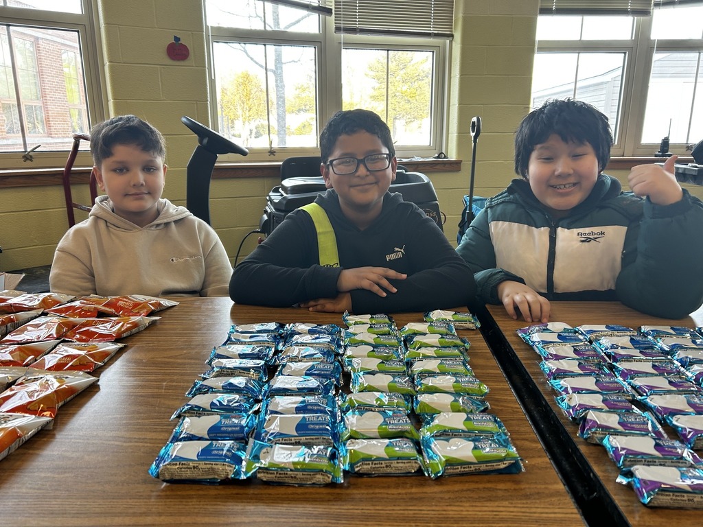 Kids sitting behind a table filled with snacks.